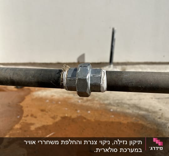 צינור מתכת עם חיבור ברזל על רקע קיר לבן